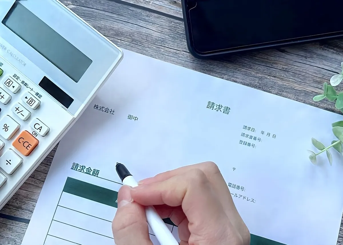 電卓を使いながら請求書を書く手元